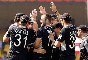 Captain Daniel Vettori of New Zealand is congratulated by teammates after getting the wicket of Regis Chakabva