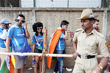 Security forces look on as fans queue outside the M. Chinnaswamy Stadium stadium in Bangalore
