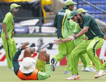 Pakistan captain Shahid Afridi (R) laughs after tackling coach Waqar Younis (C) during a practice session
