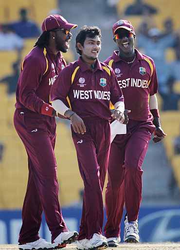 Devendra Bishoo (C) celebrates with team mates Chris Gayle and Darren Sammy