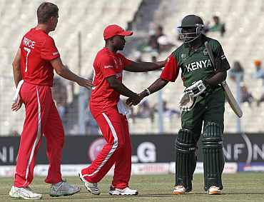 Kenya's Tikolo shakes hands with Kenya's Utseya and Price as he leaves the field following his dismissal