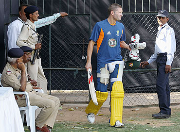 Australia's Michael Clarke walks past policemen during a nets session at Sardar Patel Stadium, Ahmedabad on Tuesday
