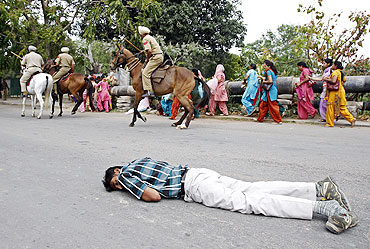 An injured man lies on a road as police mounted on horseback charge at protesters in Mohali