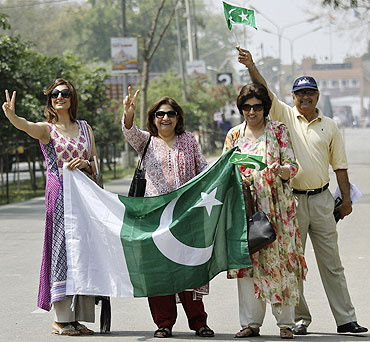 Fans hold Pakistan's national flags as they arrive in India through the India-Pakistan joint check post at the Wagah border