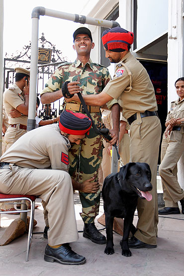 Indian security forces and their dogs are checked as they turn up to work at the Punjab Cricket Association Ground on Tuesday