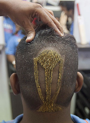 A barber shaves the head of a cricket fan into the shape of the World Cup trophy in Mumbai