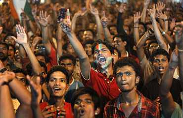 Fans react as they watch the ICC World Cup semi-final match between India and Pakistan on a screen in Mumbai