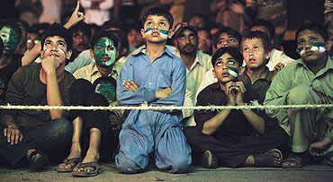 Young Pakistani cricket fans watch the semi-final between India and Pakistan on a roadside in Karachi on Wednesday