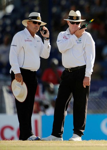 Umpires Daryl Harper (L) and Russell Tiffin (2nd L) wait for a referral verdict