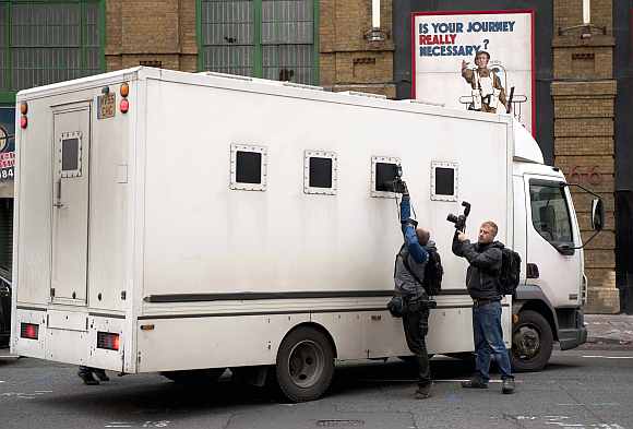 Photographers take pictures through the window of a prison van as it leaves Southwark Crown court in London
