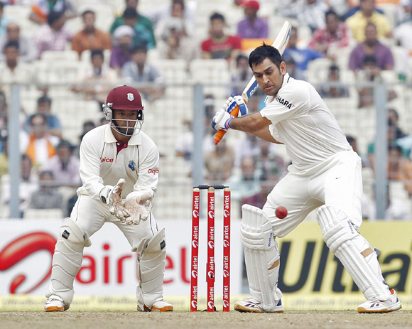 Dhoni (R) plays a shot as West Indies' wicketkeeper Carlton Baugh watches