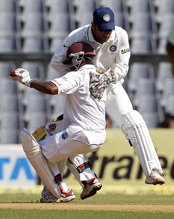 Dhoni (right) collides with the West Indies' Adrian Barath