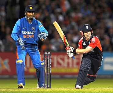 Eoin Morgan plays a sweep shot as MS Dhoni was looks on