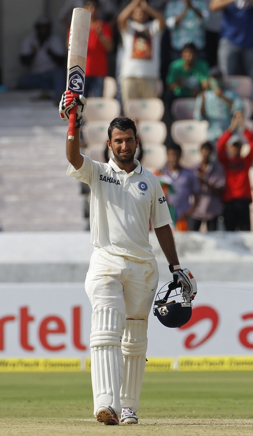 Pujara raises his bat to celebrate scoring a century
