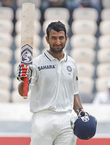 India's Cheteshwar Pujara raises his bat to celebrate scoring 150 runs during the second day of their first test cricket match against New Zealand in Hyderabad