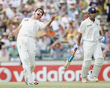 Mitchell Starc (left) of Australia celebrates after taking the wicket of Vinay Kumar