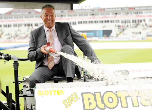Former England player and Sky commentator Sir Ian Botham sprays water from a blotter as rain delayed the start of the third day of the third Ashes cricket test match in August 2009