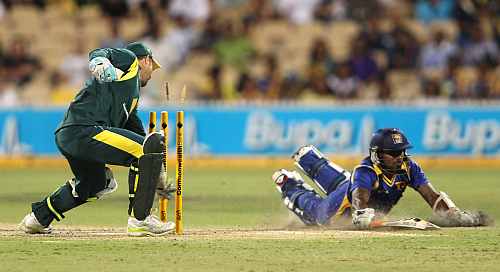 Matthew Wade of Australia breaks the stumps as Chamara Kapugedera puts in the dive during their match in Adelaide