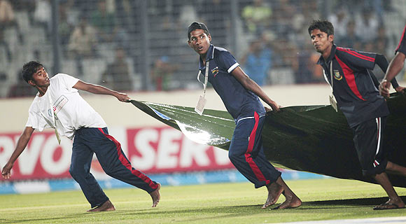 Groundsmen pull a cover sheet as rain interrupt the Asia Cup One Day International match
