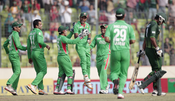 Pakistan's Mohammad Hafeez (R) leaves the field as Bangladesh's fielders celebrate his dismissal