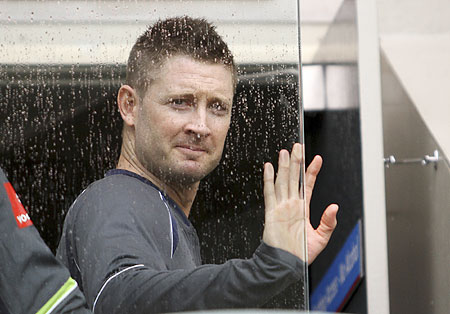 Australia's Michael Clarke looks out through a glass as it rains on the second day of the first Test against South Africa at the Gabba in Brisbane on Saturday