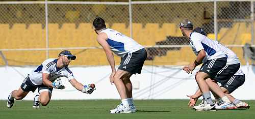 Wicketkeeper Matt Prior (L) of England goes for a catch during a slip fielding drill in a nets session at Sardar Patel Stadium