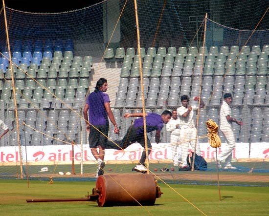 India captain MS Dhoni rolls his arm at the nets as Ishant Sharma watches