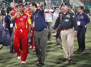 Pakistani security officials escort World XI skipper Sanath Jayasuriya (left) as he arrives to play in the first Twenty20 cricket exhibition match between Pakistan All Star XI and International World XI at the National Stadium in Karachi on Saturday