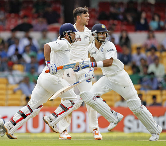 India's captain Mahendra Singh Dhoni (L) and Virat Kohli (R) run between the wickets as New Zealand's James Franklin watches during the second day of their second test cricket match against in Bangalore