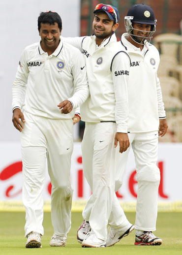 India's Pragyan Ojha (left) celebrates with teammates Virat Kohli (C) and Cheteshwar Pujara