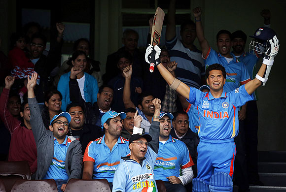 Members of the Indian cricket supporters group known as the 'Swami Army' cheer as they sit next to a wax figure of Indian cricketer Sachin Tendulkar during a promotional event at the Sydney Cricket Ground on Saturday