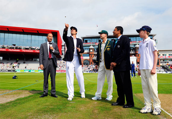 Captain Alastair Cook of England tosses the coin, watched by Australia captain Michael Clarke, commentator Nasser Hussain (L) and match referee Ranjan Madugalle