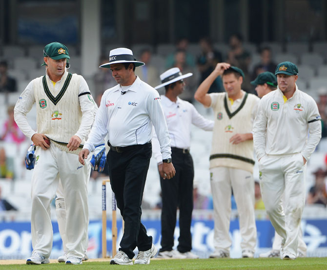 Michael Clarke of Australia talks to umpire Aleem Dar as he walks out into the field with team mates during day five