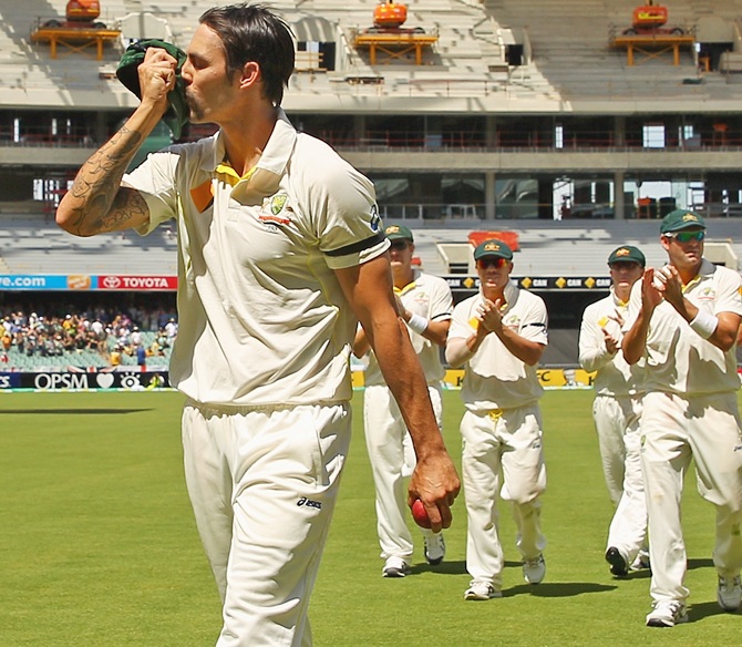 Mitchell Johnson of Australia kisses his cap as he leads his team from the field after bowling out England