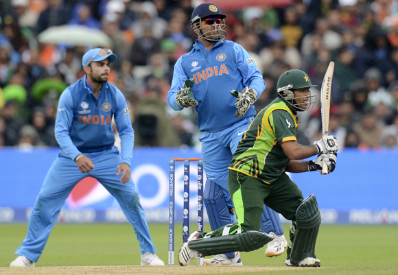 Pakistan's Asad Shafiq (right) hits out watched by India's Virat Kohli (left) and Mahendra Singh Dhoni