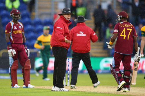 Umpire Steve Davis (2L) stops play as rain arrives as Dwayne Bravo (R) and Darren Sammy (L) of West Indies have to accept that South Africa go through to the semi-final as the match is tied on the Duckworth/Lewis method