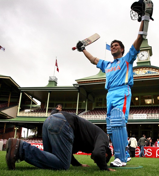 An Indian cricket supporter kneels in front of a wax figure of Indian cricketer Sachin Tendulkar