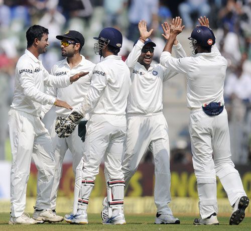 Pragyan Ojha is congratulated by teammates after picking his fifth wicket