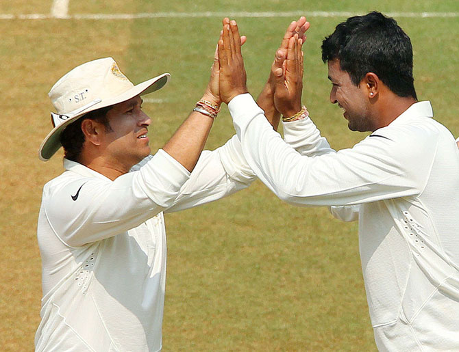 Pragyan Ojha of India celebrates the wicket of Kieran Powell of West Indies with Sachin Tendulkar