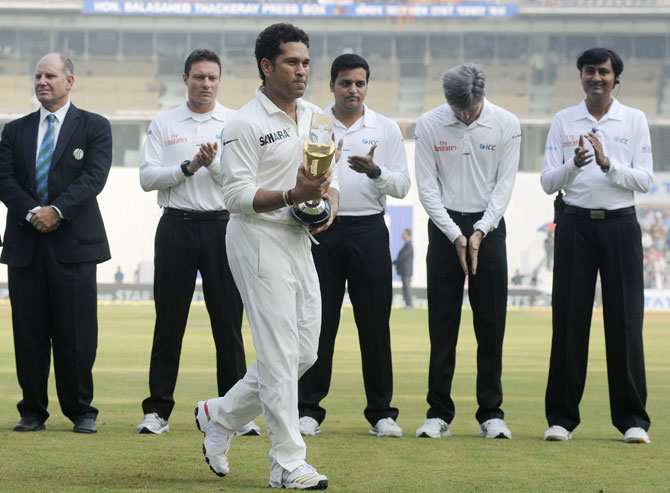 Sachin Tendulkar of India walks back with the trophy during a felicitation before the start of play on day one