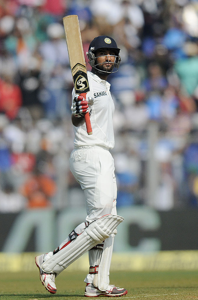 Cheteshwar Pujara of India raises his bat after scoring a half century on Friday