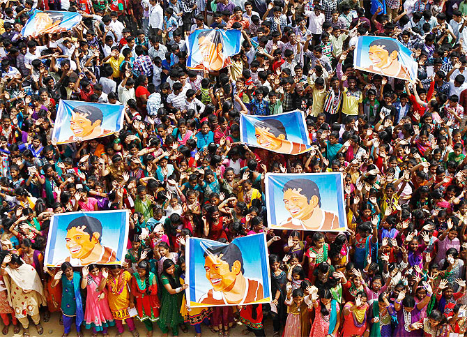 School children wave as they hold posters of Sachin Tendulkar at an event to honour him inside a school in Chennai