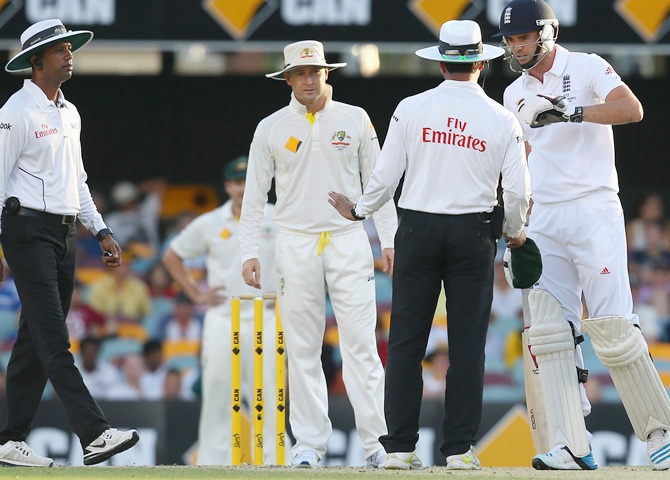 Umpire Kumar Dharmasena and Michael Clarke of Australia look on as Umpire Aleem Dar speaks to James Anderson of England after a verbal altercation