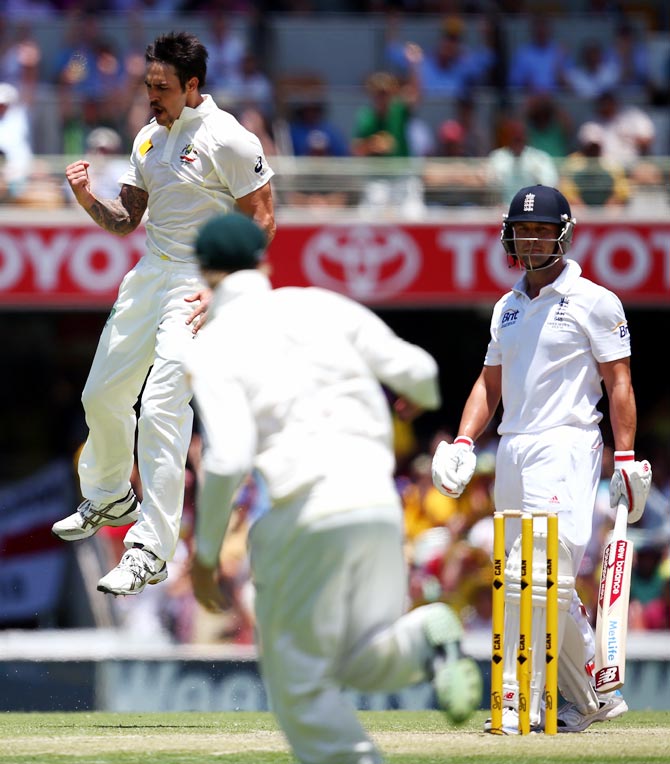 Mitchell Johnson (left) celebrates after taking the wicket of Jonathan Trott (right).