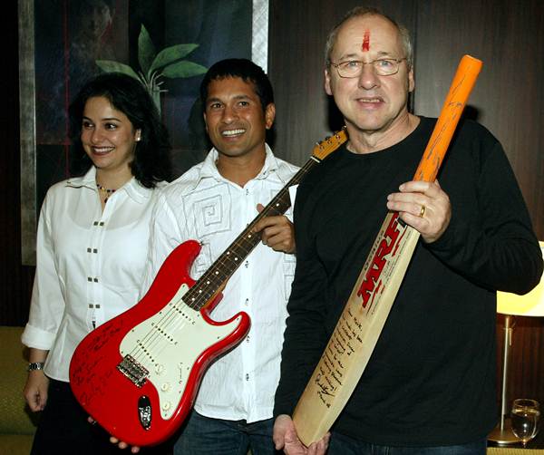 Former Dire Straits lead singer and guitar legend Mark Knopfler with Sachin Tendulkar pose with a bat and guitar, which they gave each other in Bombay on March 4, 2005. Tendulkar's wife Anjali is on the left.