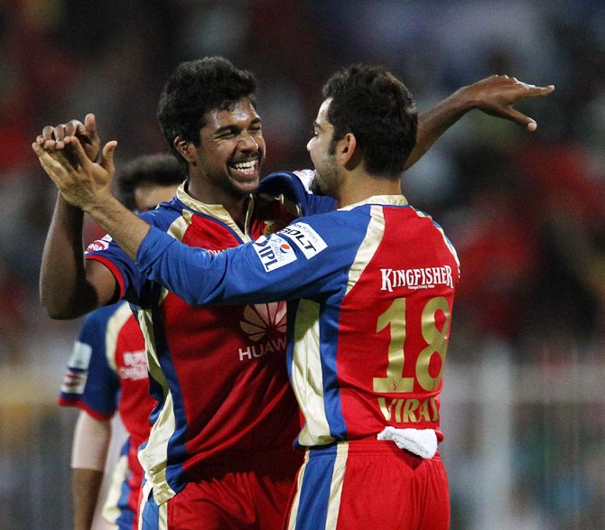 Varun Aaron celebrates with captain Virat Kohli after taking the wicket of Robin Uthappa