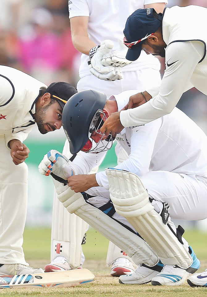 Indian fielders attend to England batsman Stuart Broad after he is hit, by a Varun Aaron delivery, through the grill of his helmet in the fourth Test at Old Trafford on August 9