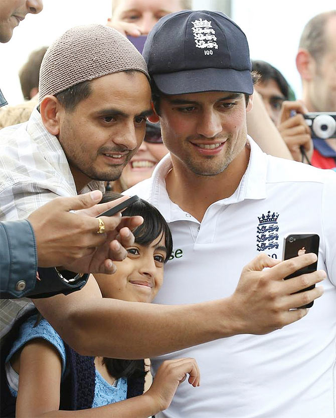 England captain Alastair Cook (right) poses for photographs with fans after defeating India in the fourth cricket Test match between England and India at Old Trafford in Manchester on August 9