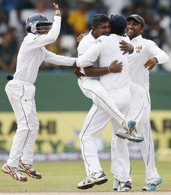 Sri Lanka's Rangana Herath (top) celebrates with captain Angelo Mathews, Mahela Jayawardene (right) and Kaushal Silva after taking the wicket of Pakistan's Asad Shafiq (not pictured) during the fourth day of their second and final Test match in Colombo on Sunday