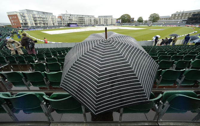 A spectator sits under an umbrella waiting for play to start in Bristol